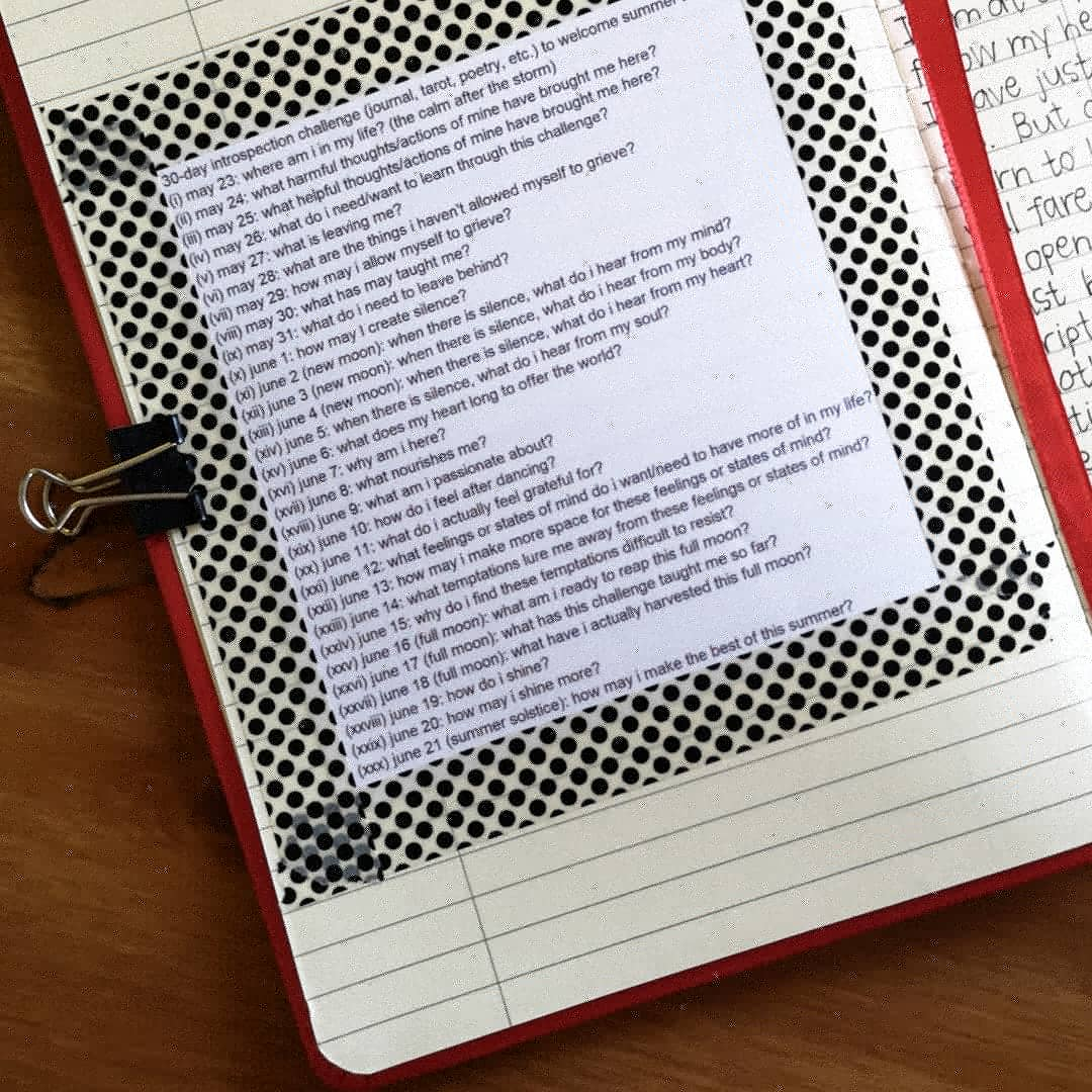 picture of one of my notebooks. i printed out the list of prompts for the 30-day challenge and stuck it on a page with black-and-white polka-dotted washi tape.